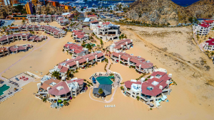 Aerial view of the sprawling beachfront condo resort in Cabo San Lucas, showing its multiple buildings, pools, and the nearby marina.