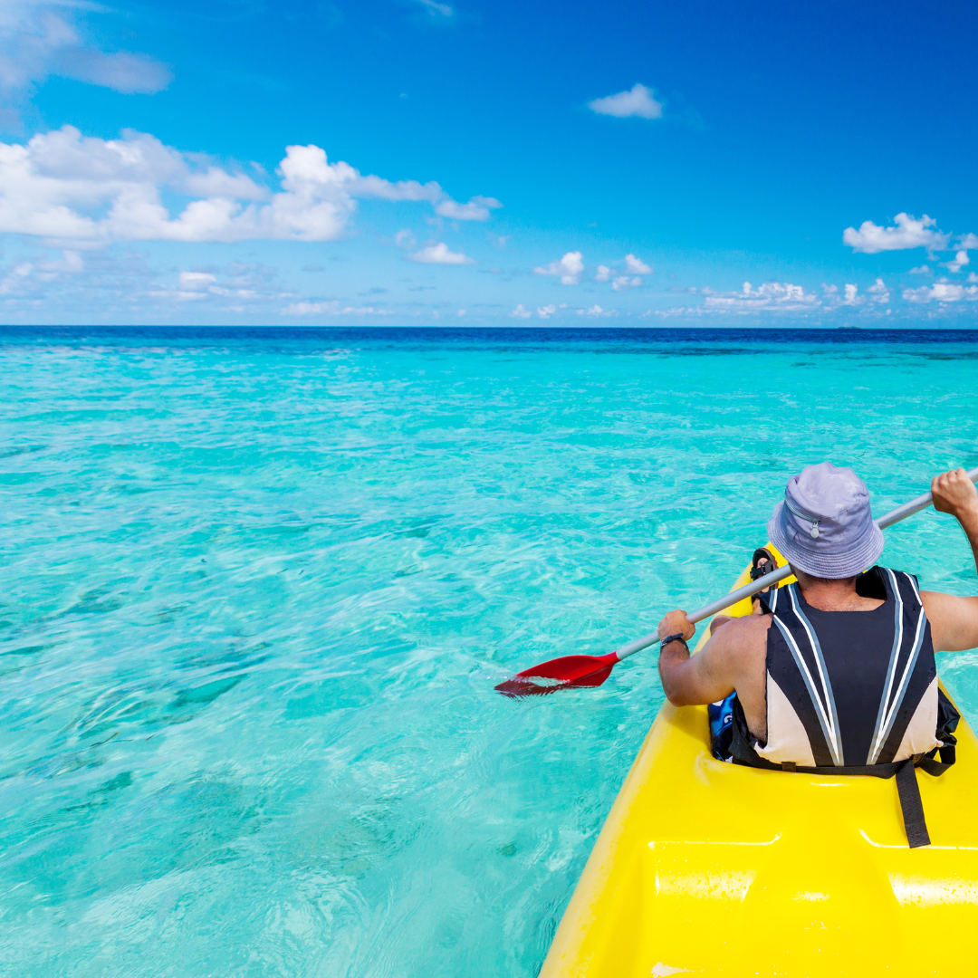 kayaking-cabo-fitness-retreats A person kayaking in brilliant turquoise waters, an invigorating activity offered at Cabo fitness retreats.