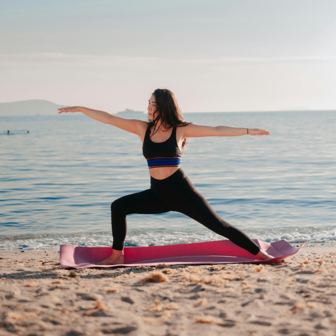 yoga-and-wellness-retreats-cabo A woman practices a yoga pose on the beach, a key part of the yoga & wellness retreats in Cabo.