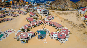 Aerial view of the sprawling beachfront condo resort in Cabo San Lucas, showing its multiple buildings, pools, and the nearby marina.