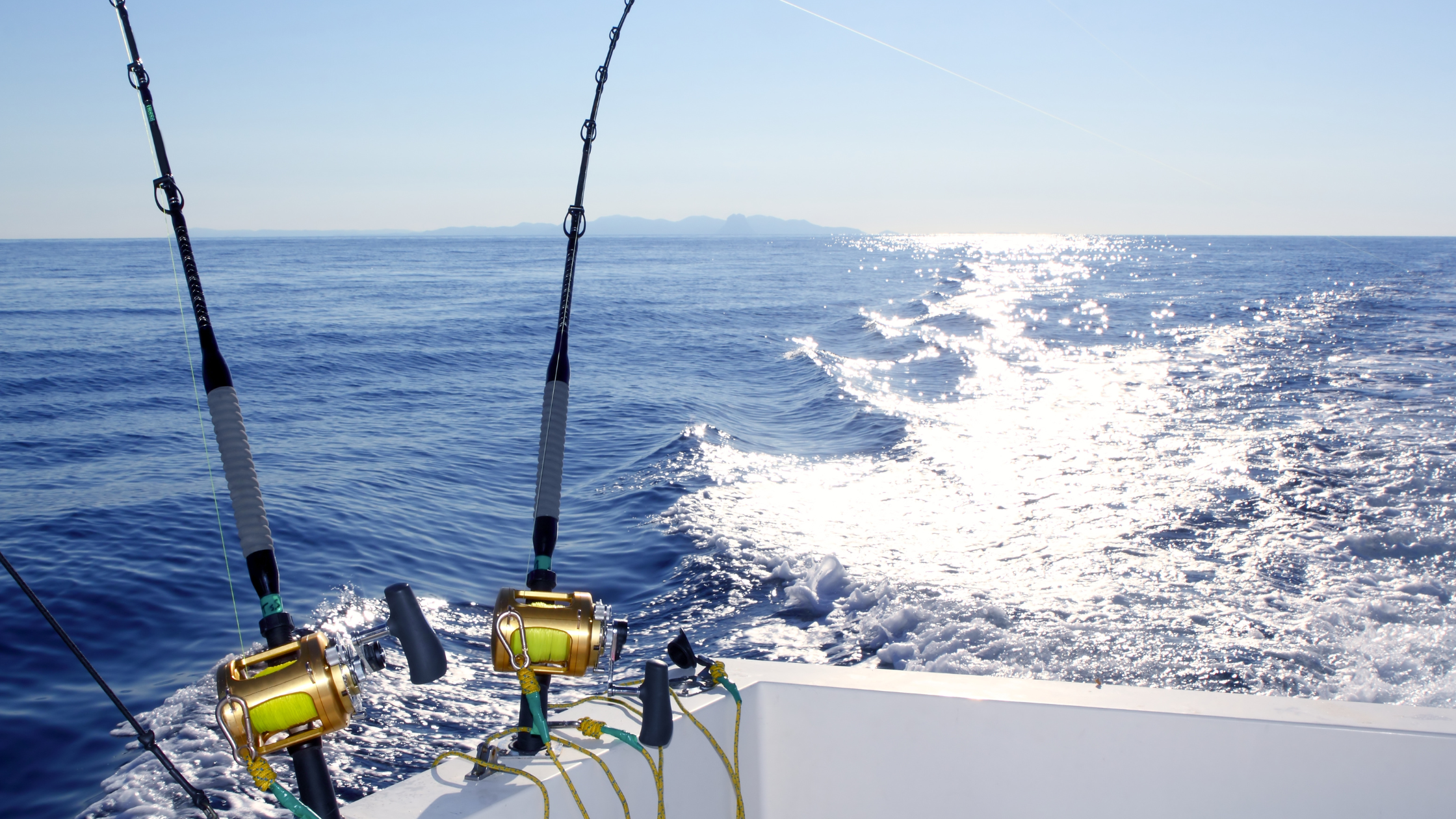 Two mounted sportfishing rods on a boat stern in the middle of the ocean.