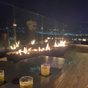 Bar en la azotea con chimeneas y vistas a las luces de la ciudad de Cabo San Lucas. Un elegante local nocturno cerca de los alquileres vacacionales de Cabo San Lucas.